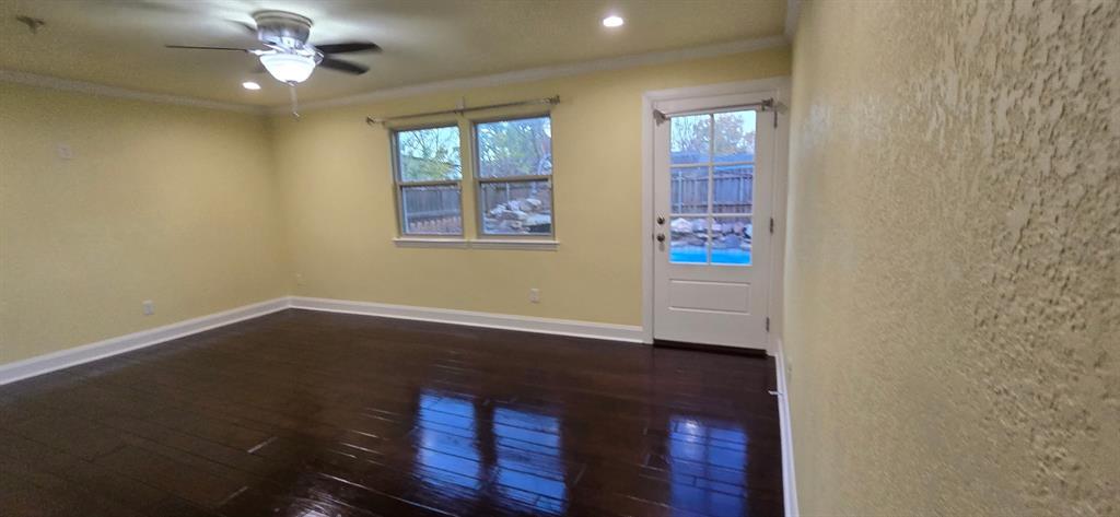 509 Royal Valley Road Grand Prairie, TX 75052 - Photo 8 of 22 an empty room with wooden floor chandelier fan and windows