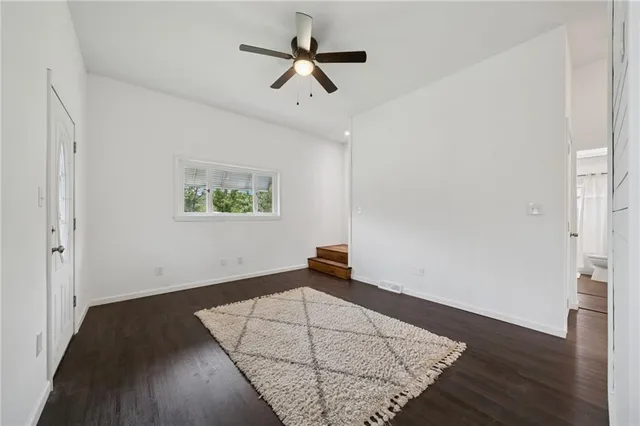 an empty room with wooden floor ceiling fan and windows