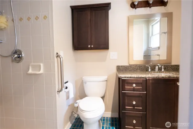 a bathroom with a granite countertop toilet sink and mirror