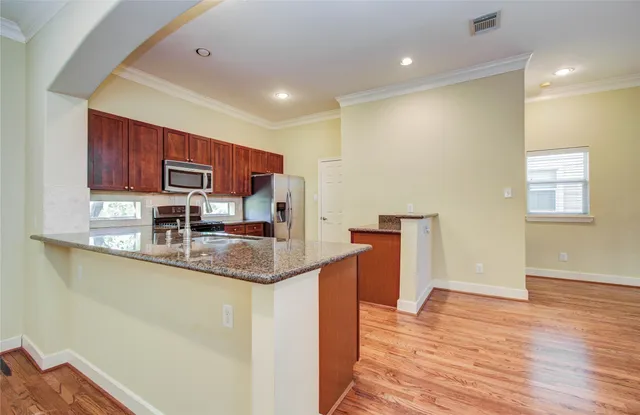 a kitchen with stainless steel appliances granite countertop a sink a stove a refrigerator cabinets and wooden floor