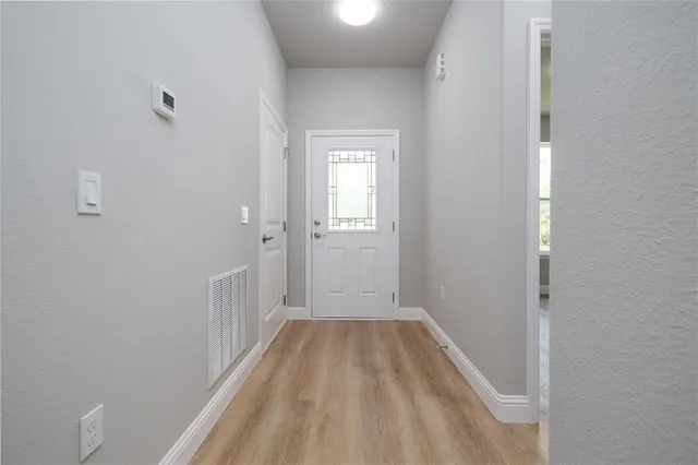 a view of a hallway with wooden floor and a bathroom
