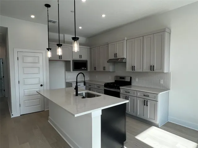 a kitchen with stainless steel appliances granite countertop a sink a stove and a refrigerator