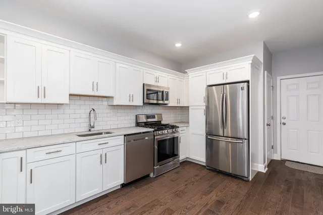 a kitchen with a refrigerator sink and white cabinets
