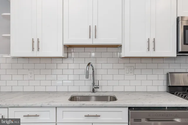 a kitchen with white cabinets a sink and dishwasher