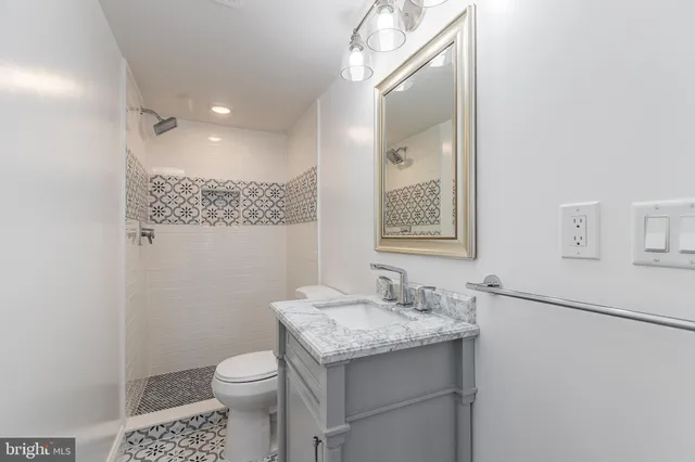 a bathroom with a granite countertop sink a toilet and a mirror