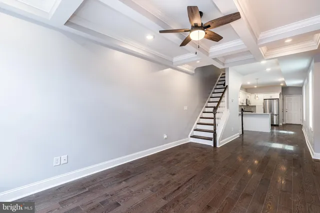 a view of an empty room with stairs and a ceiling fan