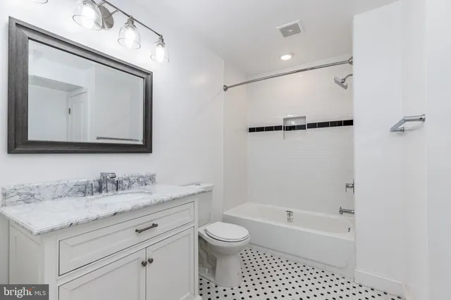 a bathroom with a granite countertop sink a toilet and a mirror