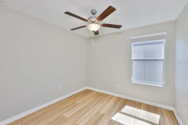 an empty room with a window and ceiling fan