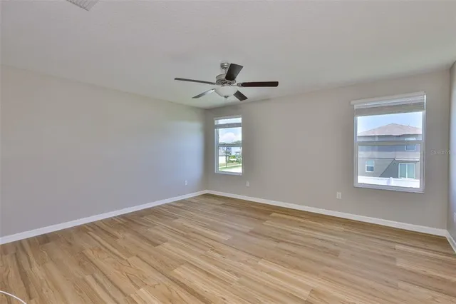 a view of empty room with wooden floor and fan