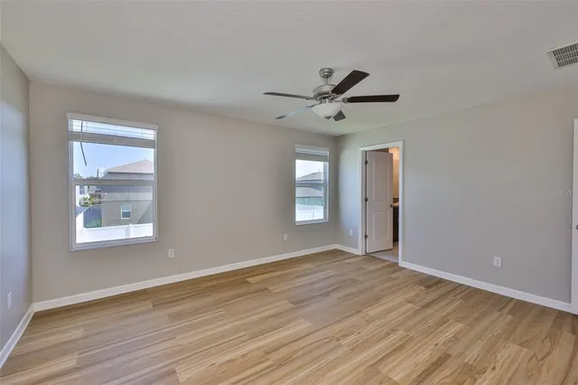 a view of empty room with wooden floor and fan