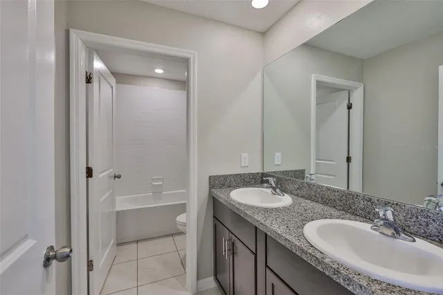 a bathroom with a granite countertop double vanity sink and mirror with shower