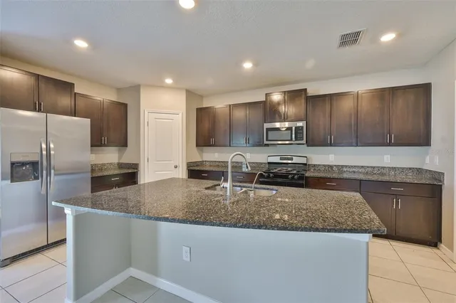 a kitchen with stainless steel appliances granite countertop a sink refrigerator and microwave