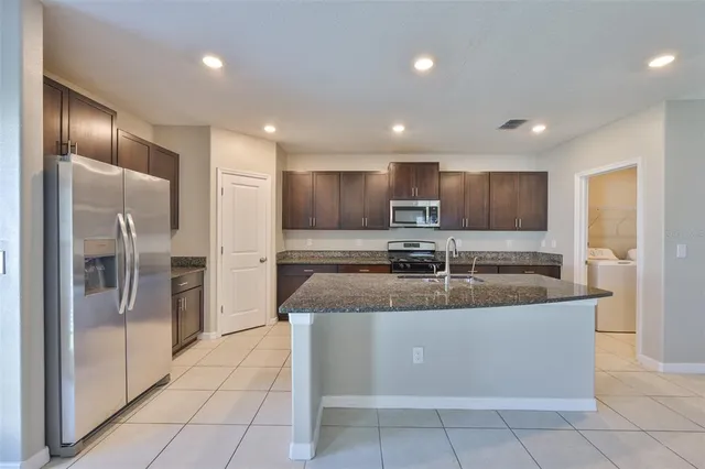 a large kitchen with granite countertop a large counter top stainless steel appliances and cabinets