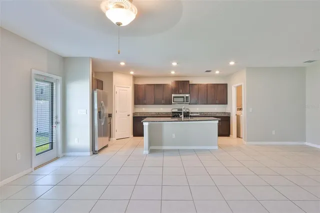 a large kitchen with a large counter top a sink stainless steel appliances and cabinets