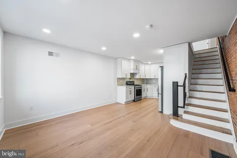 a view of kitchen with wooden floor electronic appliances and stairs