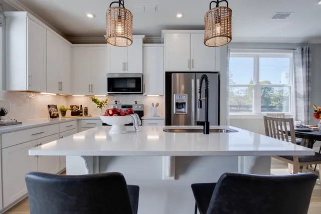 a kitchen with stainless steel appliances a dining table chairs a refrigerator and microwave