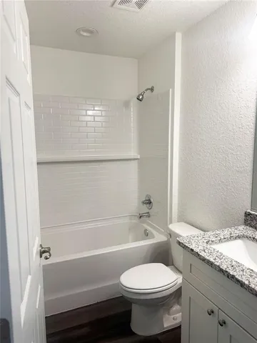 a bathroom with a granite countertop toilet a sink and bathtub