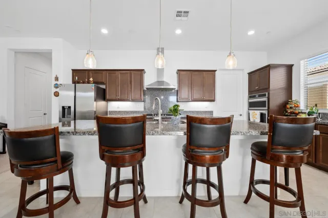 a kitchen with stainless steel appliances kitchen island granite countertop a stove a sink and a refrigerator