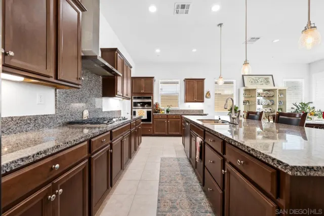 a kitchen with stainless steel appliances kitchen island granite countertop a dining table chairs and a refrigerator