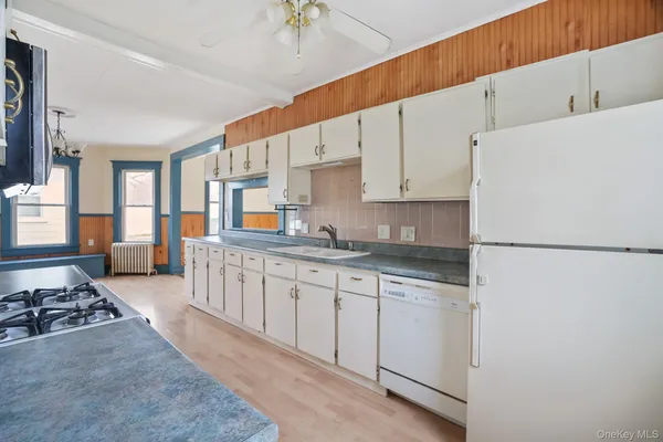 a kitchen with granite countertop a refrigerator a sink a stove and white cabinets