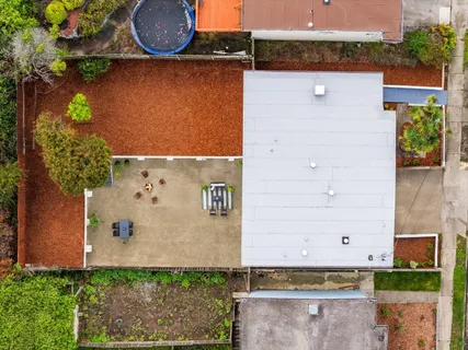 an aerial view of a house with a yard and a large tree