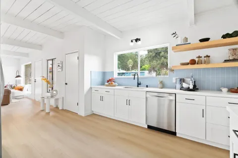 a kitchen with white cabinets and window