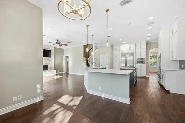 a large kitchen with kitchen island a large counter top stainless steel appliances and a chandelier