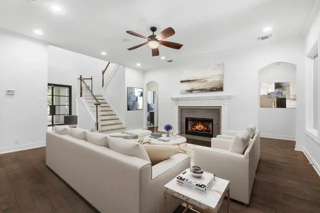 a living room with furniture a fireplace and a ceiling fan