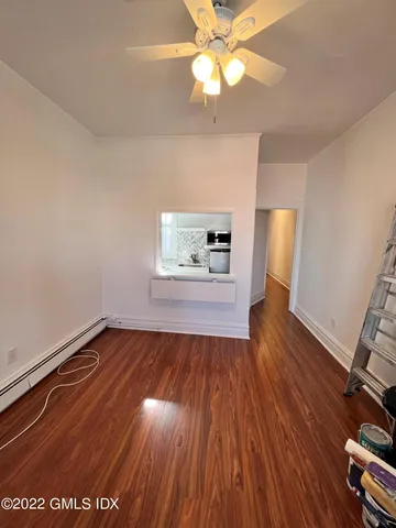 an empty room with wooden floor chandelier fan and windows