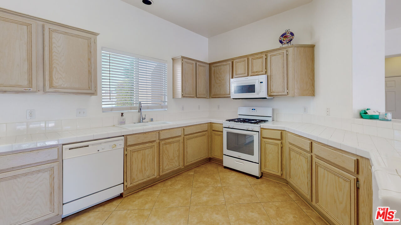 68606 La Medera Road Cathedral City, CA 92234 - Photo 7 of 33 a kitchen with granite countertop white cabinets and white appliances