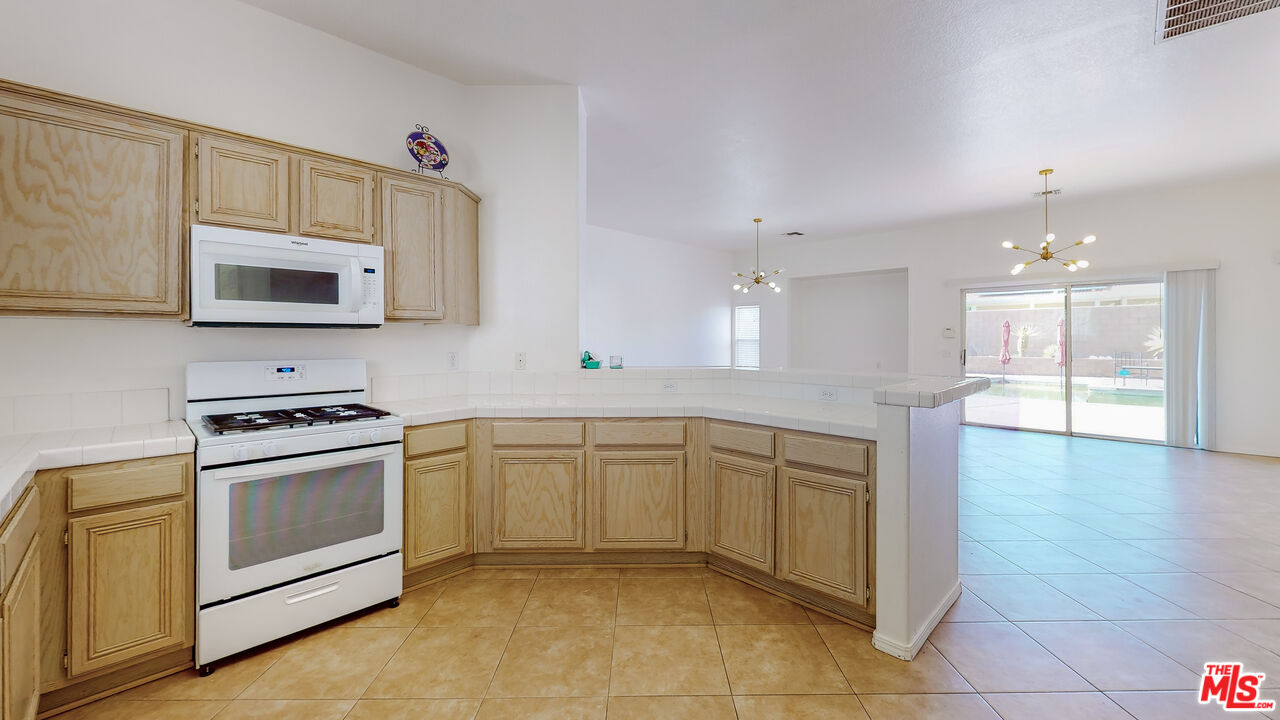 68606 La Medera Road Cathedral City, CA 92234 - Photo 10 of 33 a kitchen with stainless steel appliances granite countertop a stove a sink and a microwave