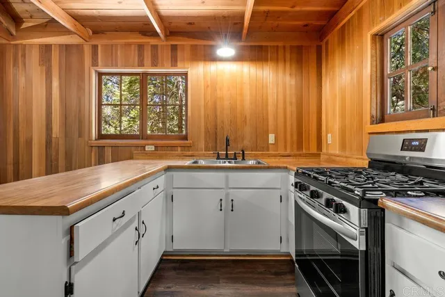 a kitchen with granite countertop a sink stainless steel appliances wooden floor and a window