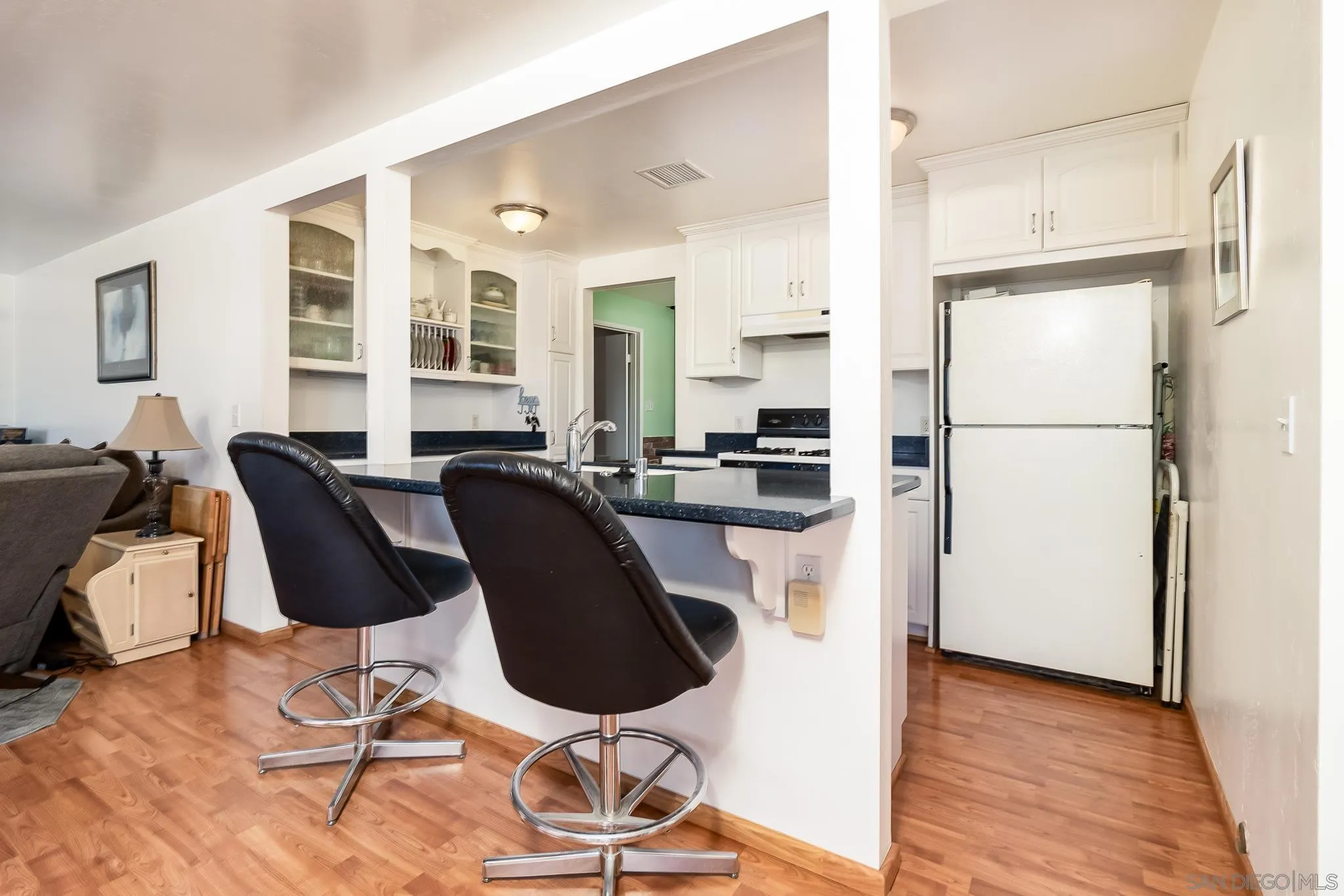 8423 Prospect Avenue Santee, CA 92071 - Photo 7 of 30 a kitchen with stainless steel appliances kitchen island granite countertop a refrigerator a stove a sink and white cabinets with wooden floor