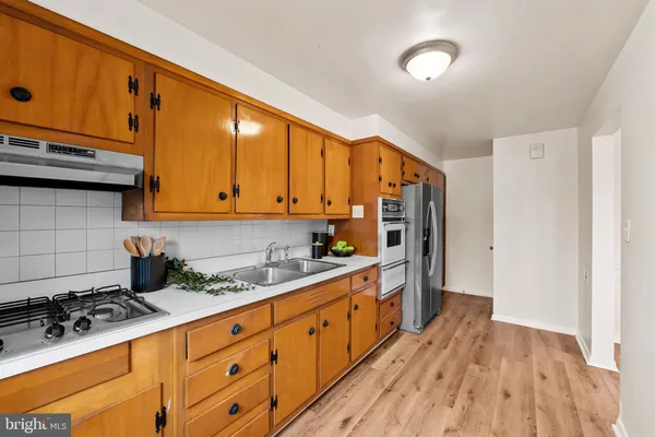 a kitchen with stainless steel appliances a stove a sink cabinets and wooden floor