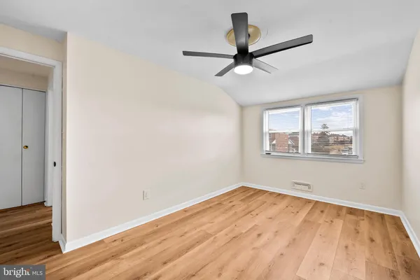 a view of empty room with wooden floor and fan