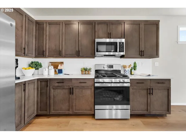 a kitchen with stainless steel appliances a stove a microwave a sink and cabinets