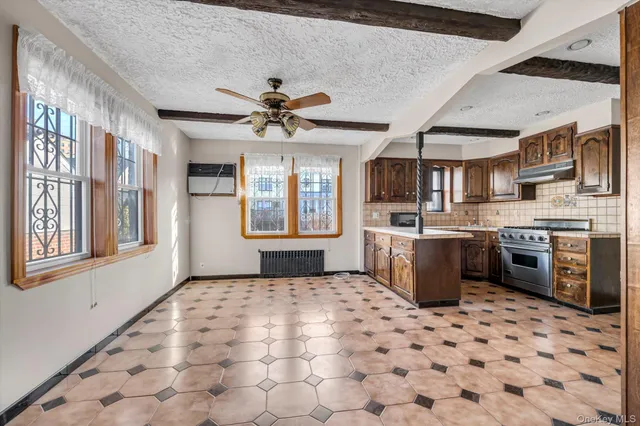 a kitchen with stainless steel appliances a sink a stove a refrigerator cabinets and a window