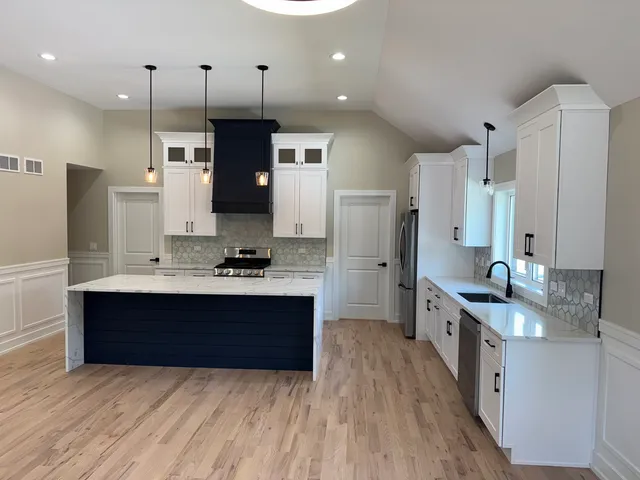 a large kitchen with stainless steel appliances granite countertop a sink stove and refrigerator