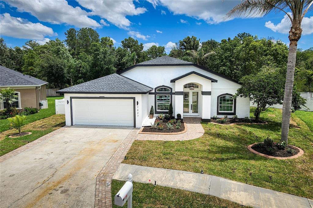 7027 Frascati Loop Wesley Chapel, FL 33544 - Photo 21 of 28 a view of a yard in front of a house with plants and large tree