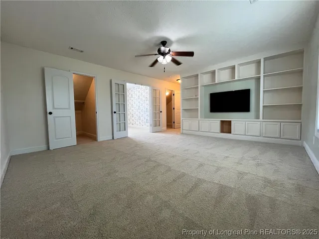 a view of a livingroom with a flat screen tv cabinets and a ceiling fan