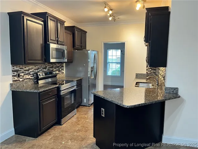 a kitchen with stainless steel appliances granite countertop a sink stove and refrigerator