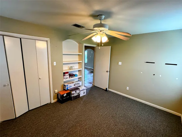 an empty room with closet and a chandelier fan