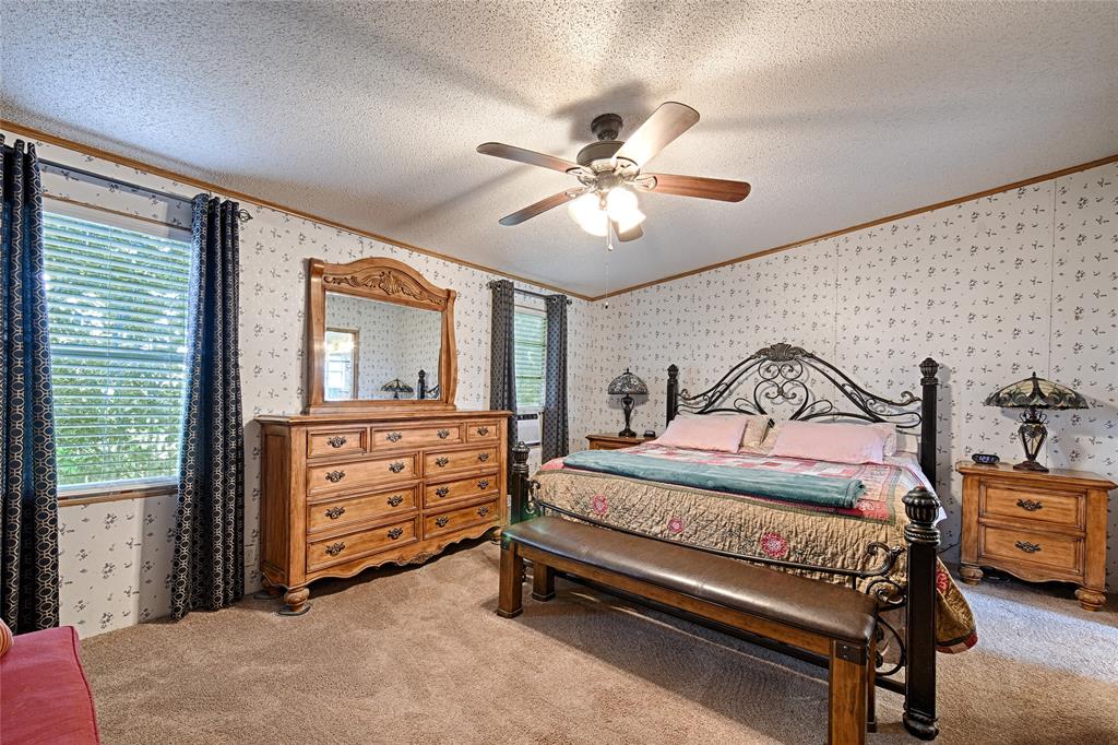 1670 Smith Circle Combine, TX 75159 - Photo 11 of 31 Bedroom featuring ornamental molding, a textured ceiling, wallpapered walls, a ceiling fan, and light colored carpet