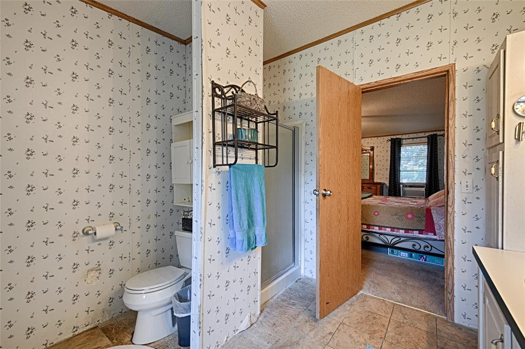 1670 Smith Circle Combine, TX 75159 - Photo 14 of 31 Bathroom featuring wallpapered walls, connected bathroom, vanity, a shower stall, and a textured ceiling