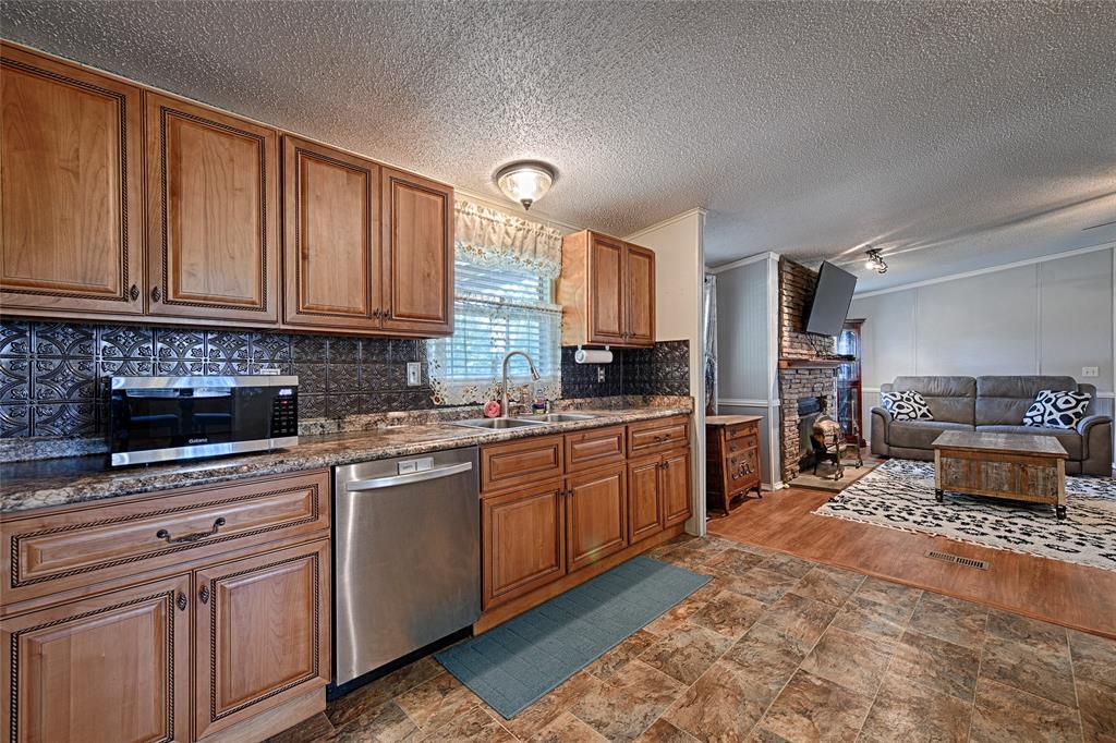 1670 Smith Circle Combine, TX 75159 - Photo 5 of 31 Kitchen featuring brown cabinets, appliances with stainless steel finishes, a fireplace, a textured ceiling, and dark stone counters