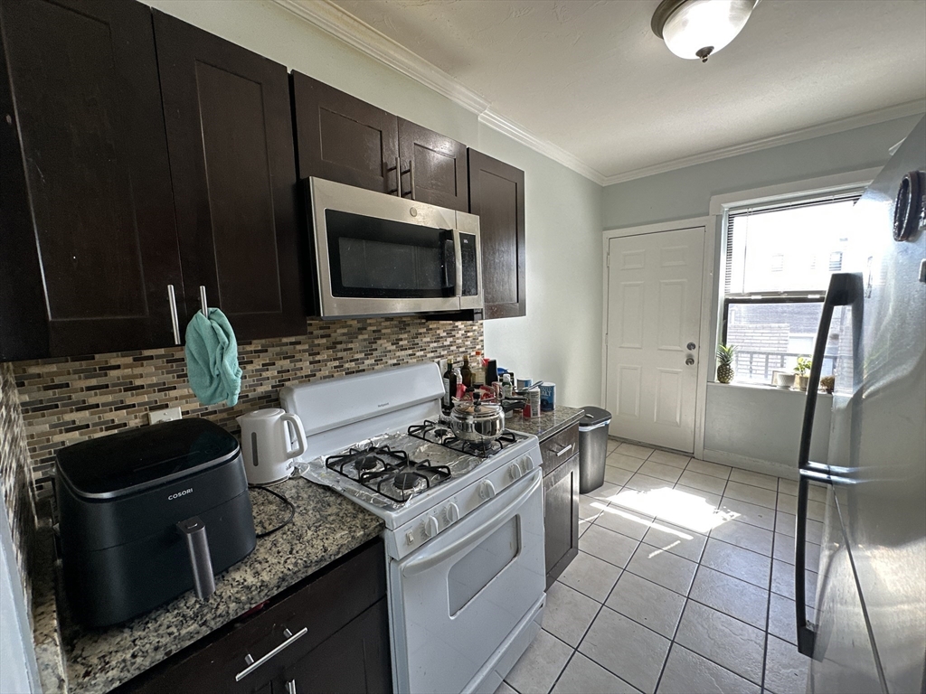 435 Walnut Avenue, Unit 10 Boston, MA 02119 - Photo 15 of 18 a kitchen with granite countertop a stove and a sink