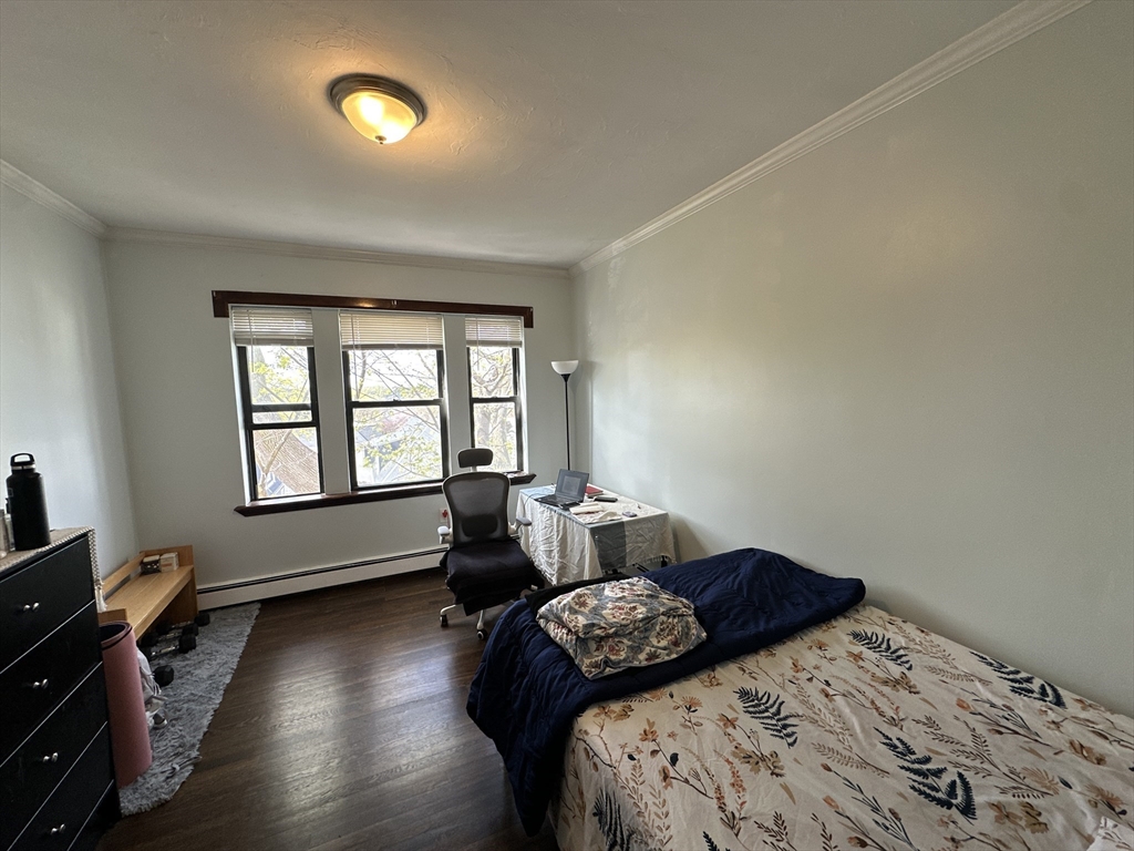 435 Walnut Avenue, Unit 10 Boston, MA 02119 - Photo 9 of 18 a bedroom with a bed and wooden floor