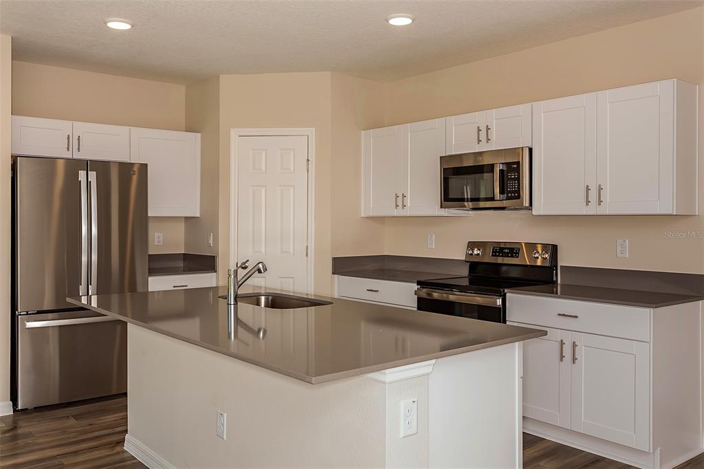 15232 Maude Lndg Loop Wimauma, FL 33598 - Photo 2 of 22 a kitchen with a sink a microwave a refrigerator and cabinets