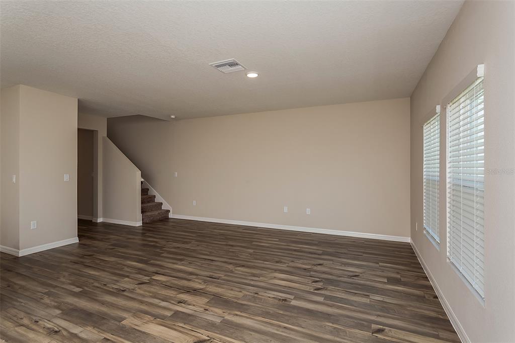 15232 Maude Lndg Loop Wimauma, FL 33598 - Photo 3 of 22 a view of an empty room with wooden floor and stairs