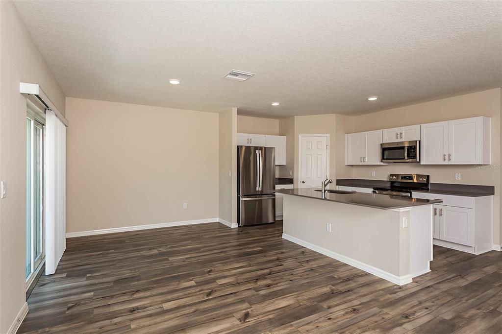 15232 Maude Lndg Loop Wimauma, FL 33598 - Photo 10 of 22 a kitchen with stainless steel appliances granite countertop a refrigerator and a stove top oven